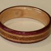Purpleheart wood ring with a maple wood interior and two inlays of maple bordering a crushed JASPER inlay