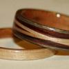 ASH.  The narrow little wood ring on the left is North American ASH with a cherry liner.  The wooden ring on the right is Greyed Maple, cherry liner, and rosewood with crossed spiraled inlays of ASH.